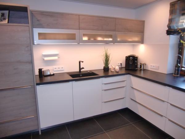 Küche in weiß mit dunkler Arbeitsplatte und braunen Hängeschränken