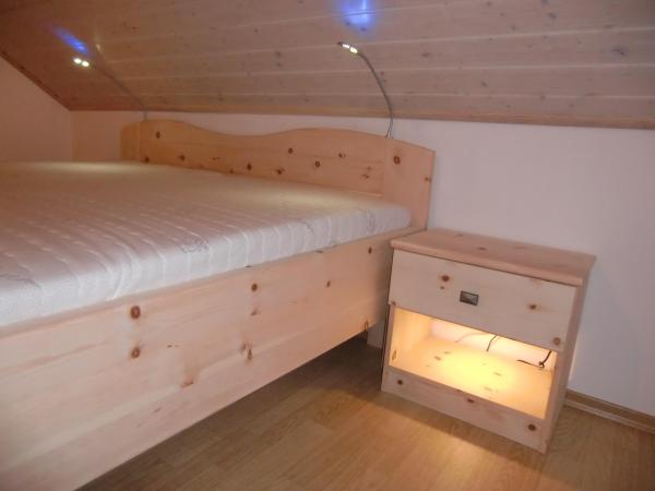 Zirbenschlafzimmer mit Bett und klassischem Nachttisch