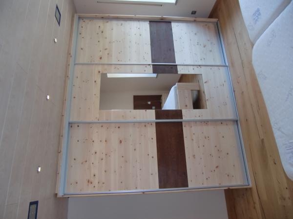 Kleiderschrank aus Zirbenholz mit braunen Elementen 