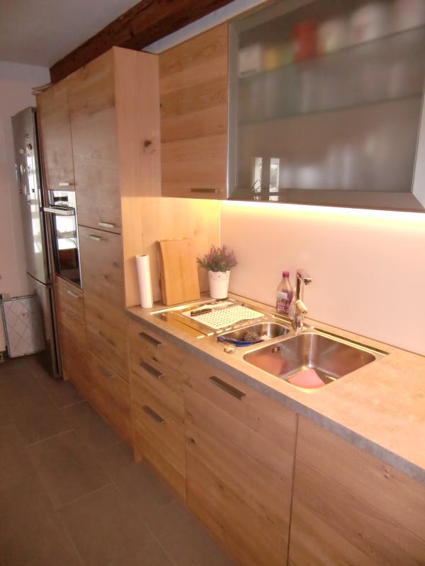 Holzküche mit heller Steinplatte und Beleuchtung
