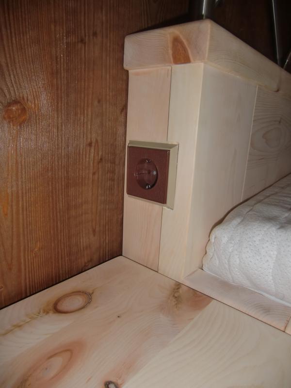 Bett mit Steckdose bei Schlafzimmer aus Zirbenholz mit braunen Elementen 