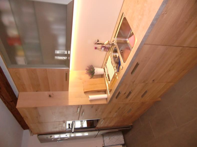 Holzküche mit heller Steinplatte mit Nahaufnahme des Waschbeckens