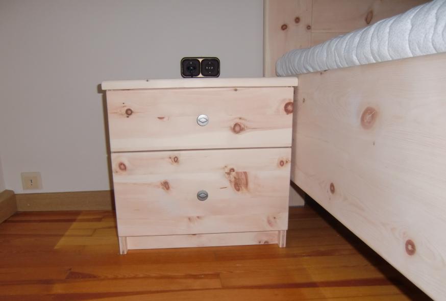 Zirbenschlafzimmer mit Bett und Nachttisch mit zwei Schubladen 