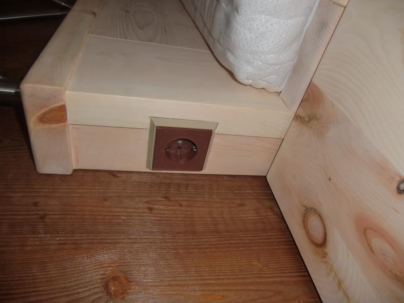 Bett mit Steckdose bei Schlafzimmer aus Zirbenholz mit braunen Elementen 