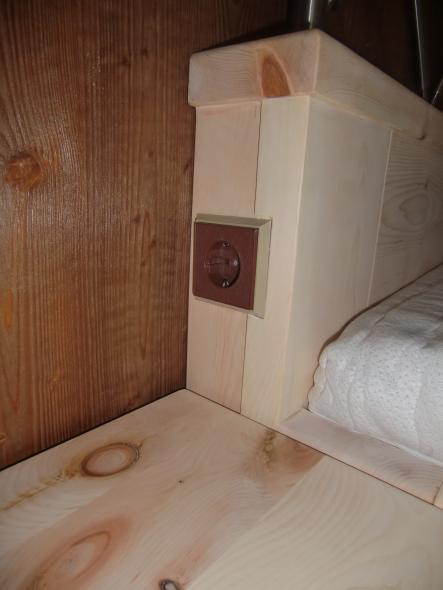 Bett mit Steckdose bei Schlafzimmer aus Zirbenholz mit braunen Elementen 